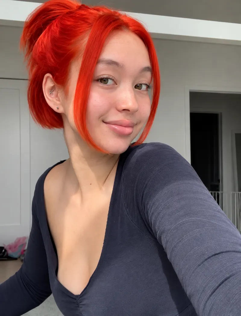 Vivid red hair color styled in a high bun with face-framing pieces