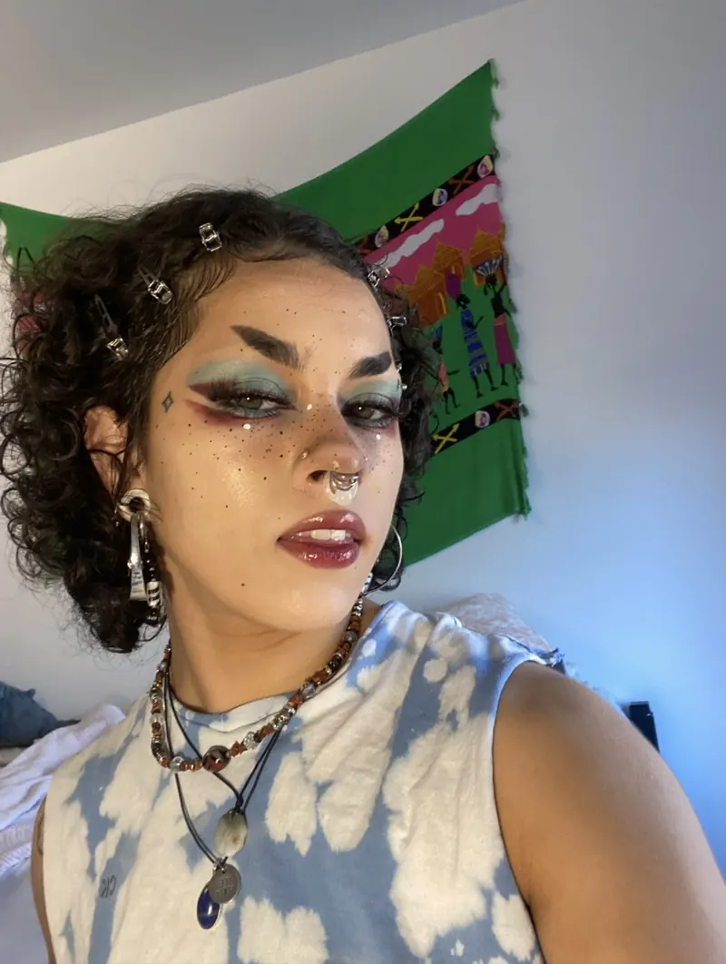 Editorial makeup look with teal graphic eyeshadow and face gems