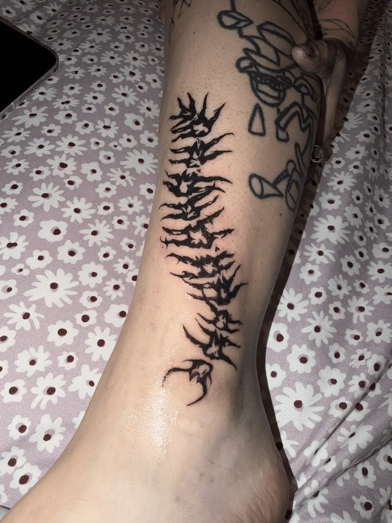 Blackwork tattoo running down the length of a client's shin